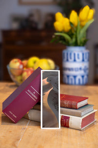 Fire Tongue fine art bookmark beside a stack of vintage books