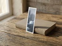 Misty Cliffs fine art bookmark resting on a linen-bound book in soft window light