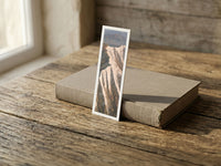 Painted Minerals fine art bookmark resting on a linen-bound book in soft window light