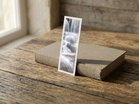 Silver Flowing fine art bookmark resting on a linen-bound book in soft window light