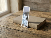 Stormy Cliffs fine art bookmark resting on a linen-bound book in soft window light