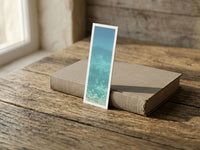 Turquoise Oceania fine art bookmark resting on a linen-bound book in soft window light