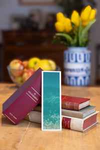 Turquoise Oceania fine art bookmark beside a stack of vintage books